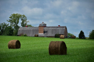 a building with bales of hay in a field